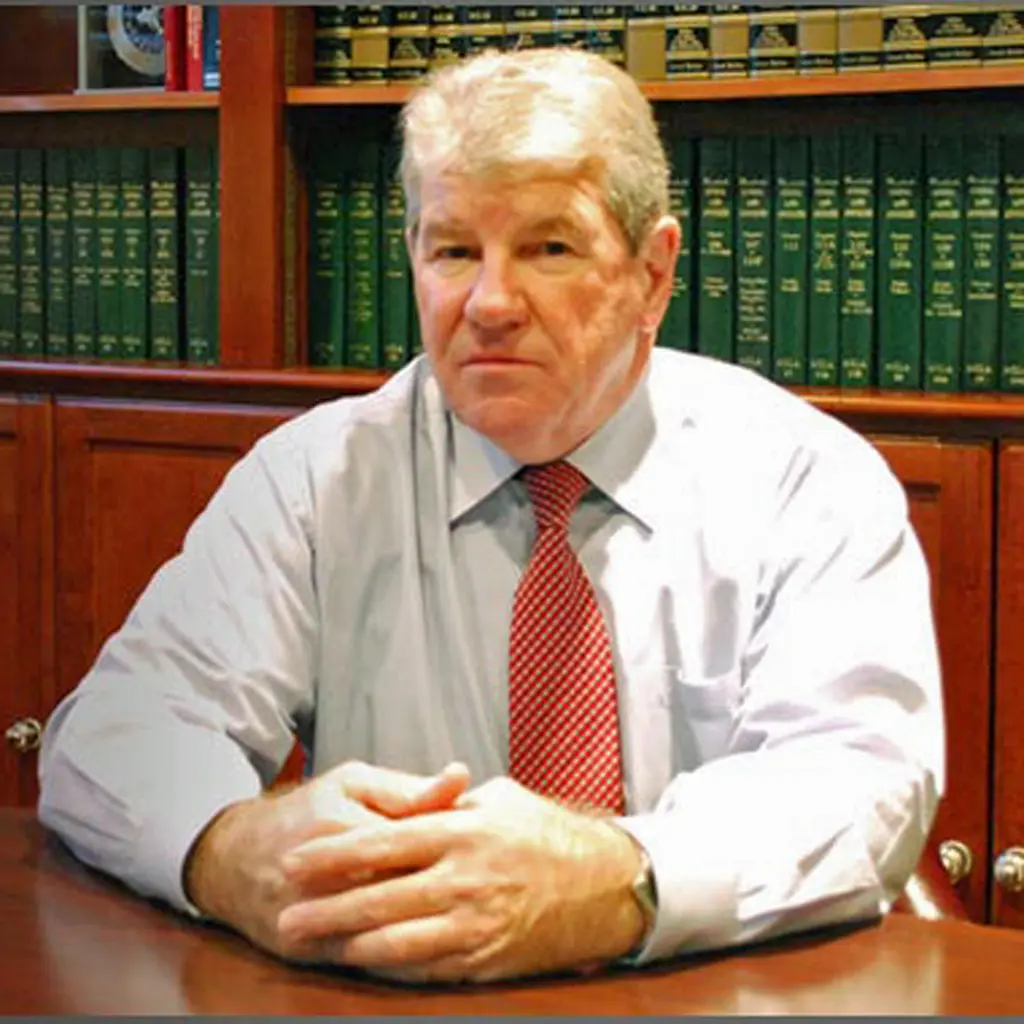 Attorney Richard Woods seated at his desk with law books in the background